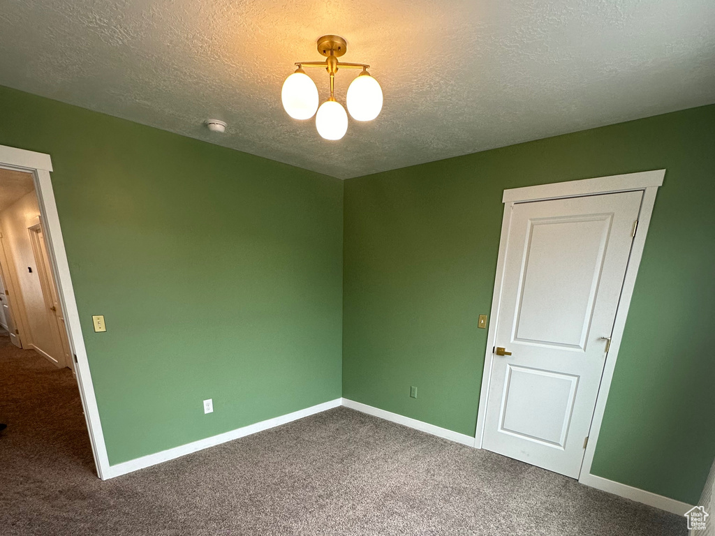 Spare room with a textured ceiling, baseboards, and carpet floors