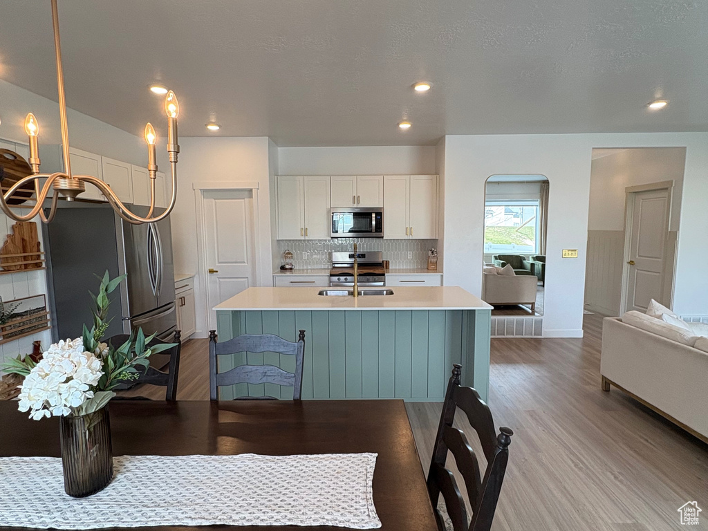Dining space with light wood-type flooring, recessed lighting, a chandelier, and baseboards