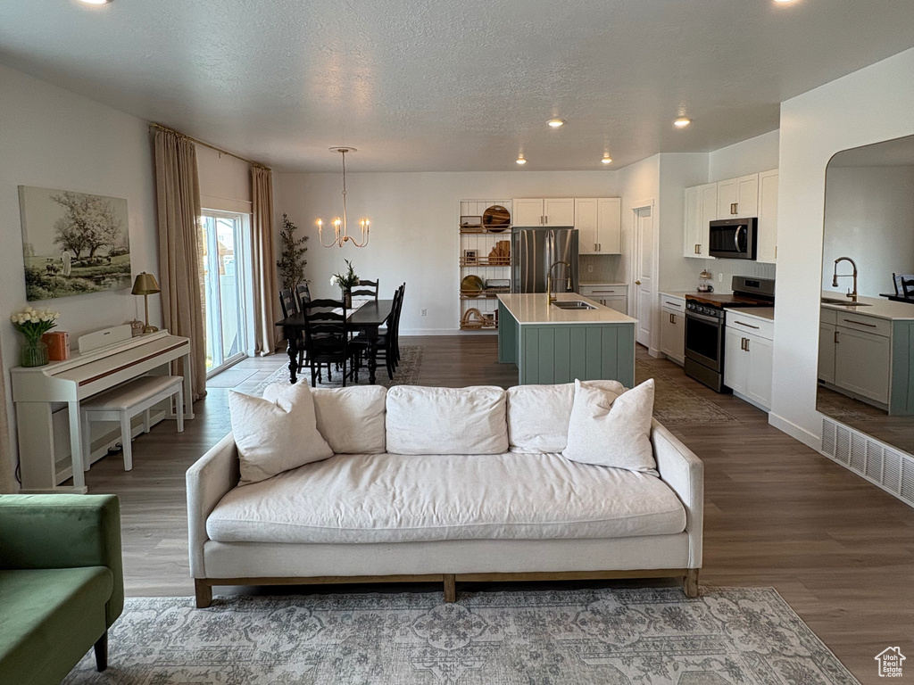 Living room featuring dark wood finished floors, recessed lighting, a chandelier, and a textured ceiling