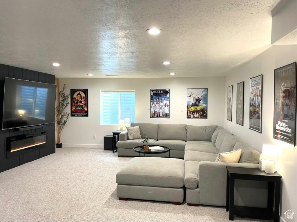 Living room with recessed lighting, carpet floors, a glass covered fireplace, and baseboards