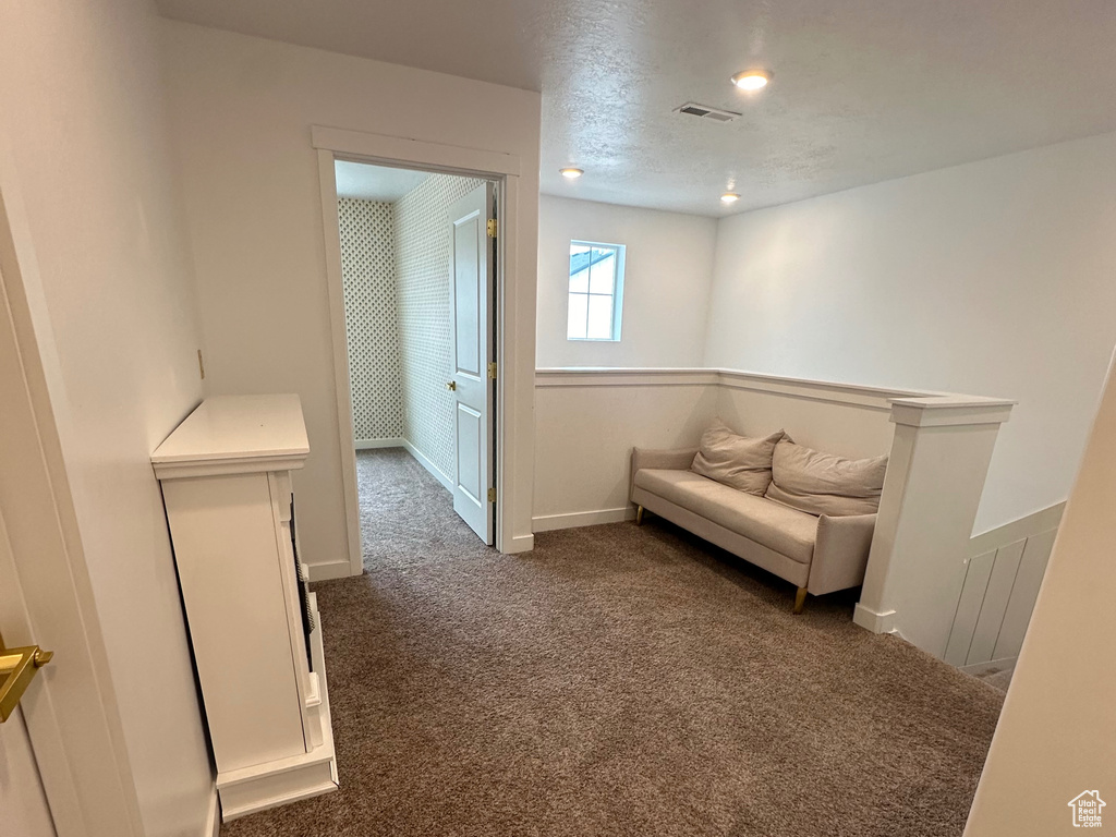 Living area featuring carpet flooring, baseboards, and an upstairs landing