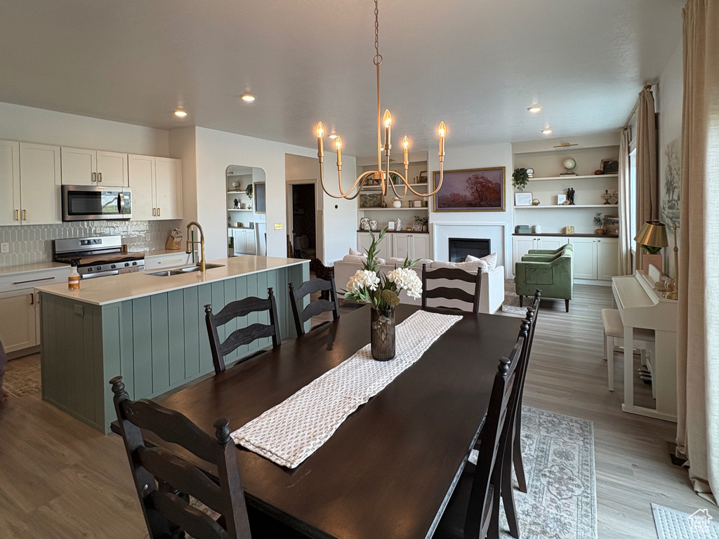 Dining area featuring a chandelier, light wood-style floors, a fireplace, and recessed lighting