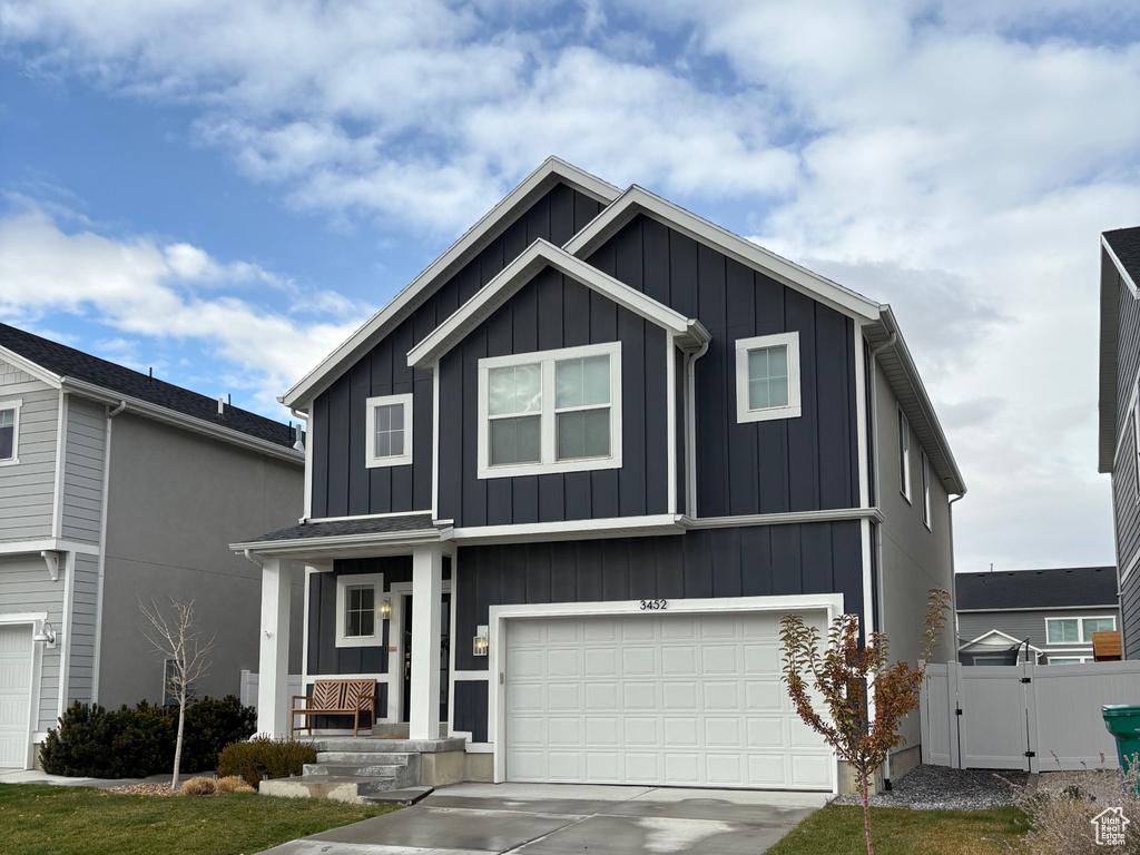 View of front of house with board and batten siding, a gate, a garage, and concrete driveway