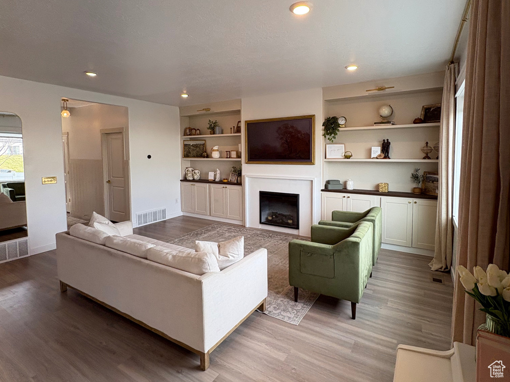 Living room with a fireplace, light wood-style flooring, recessed lighting, and built in features
