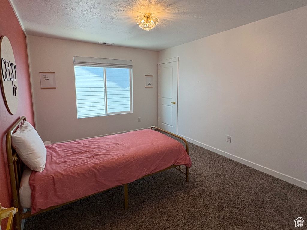 Carpeted bedroom with a textured ceiling and baseboards