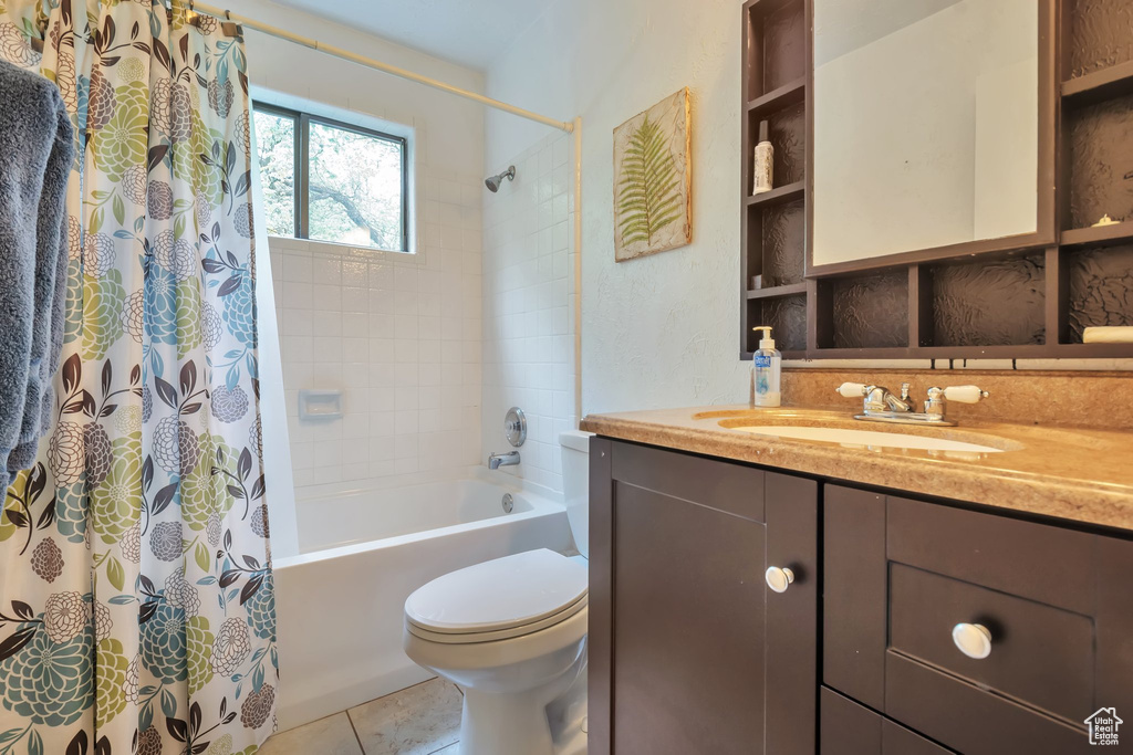 Bathroom with toilet, shower / bath combo, tile patterned flooring, and vanity