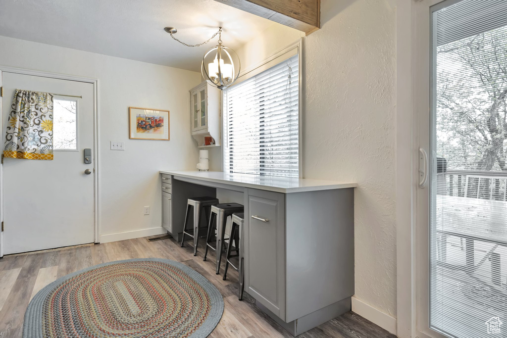 Entrance foyer with a chandelier, light wood-style flooring, a textured wall, and baseboards