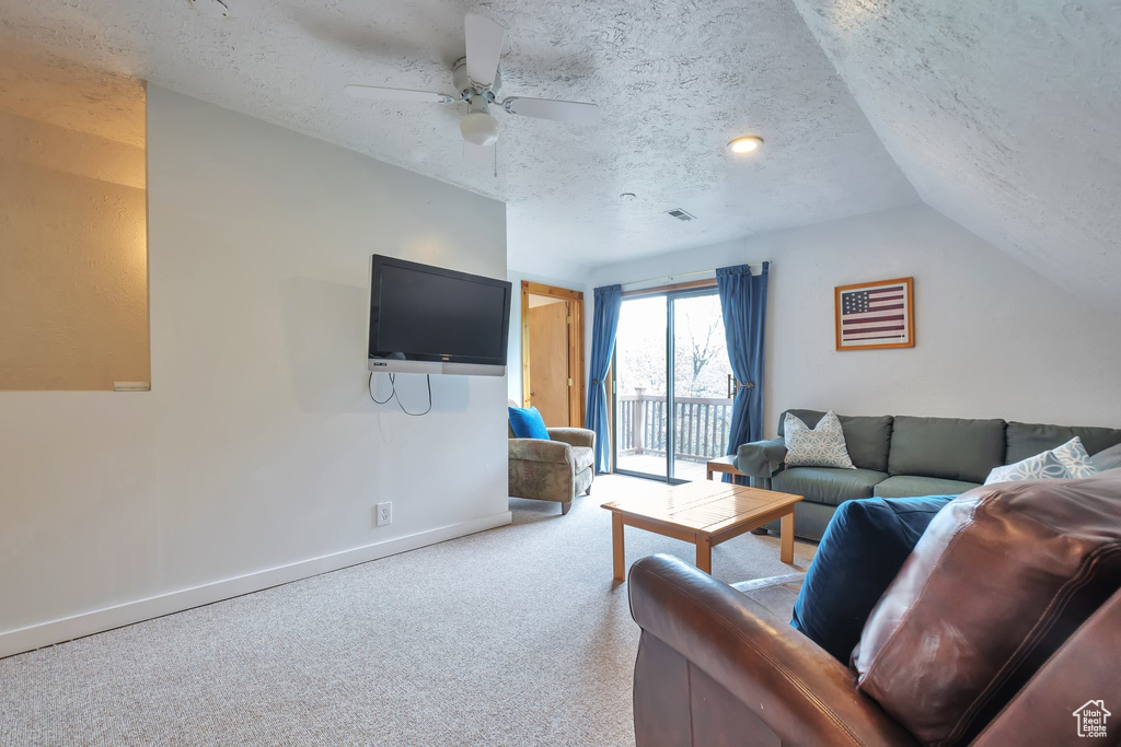 Living area with a textured ceiling, vaulted ceiling, a ceiling fan, baseboards, and carpet