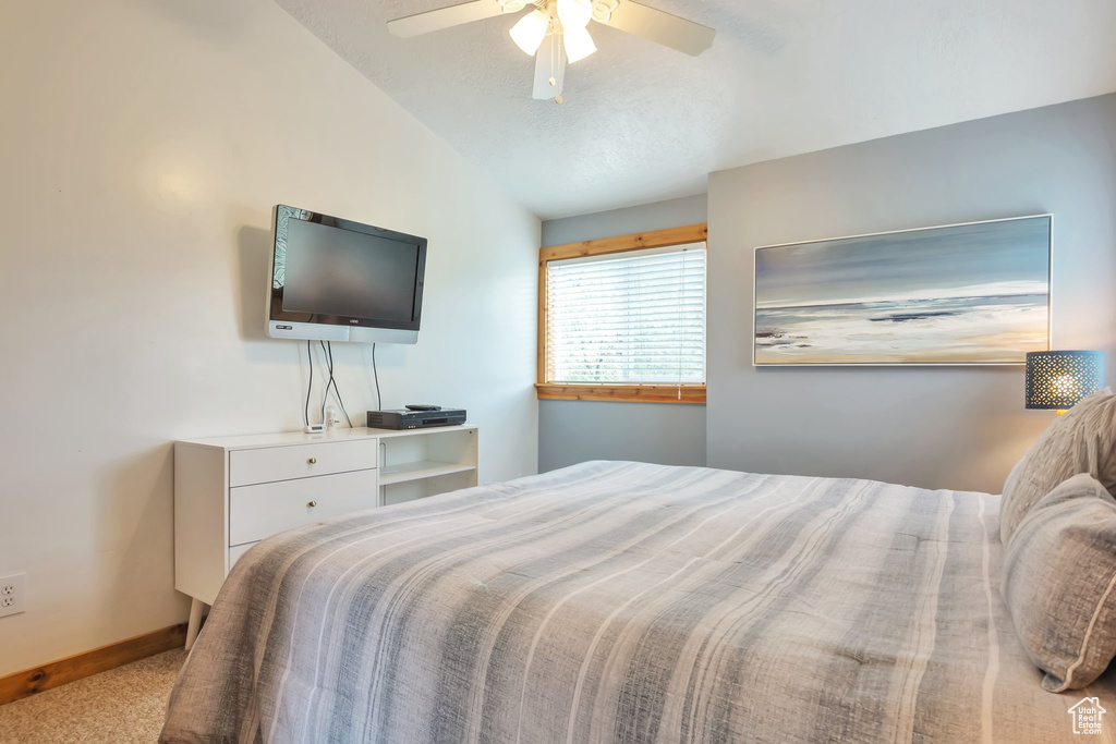 Bedroom with lofted ceiling, carpet flooring, baseboards, and ceiling fan