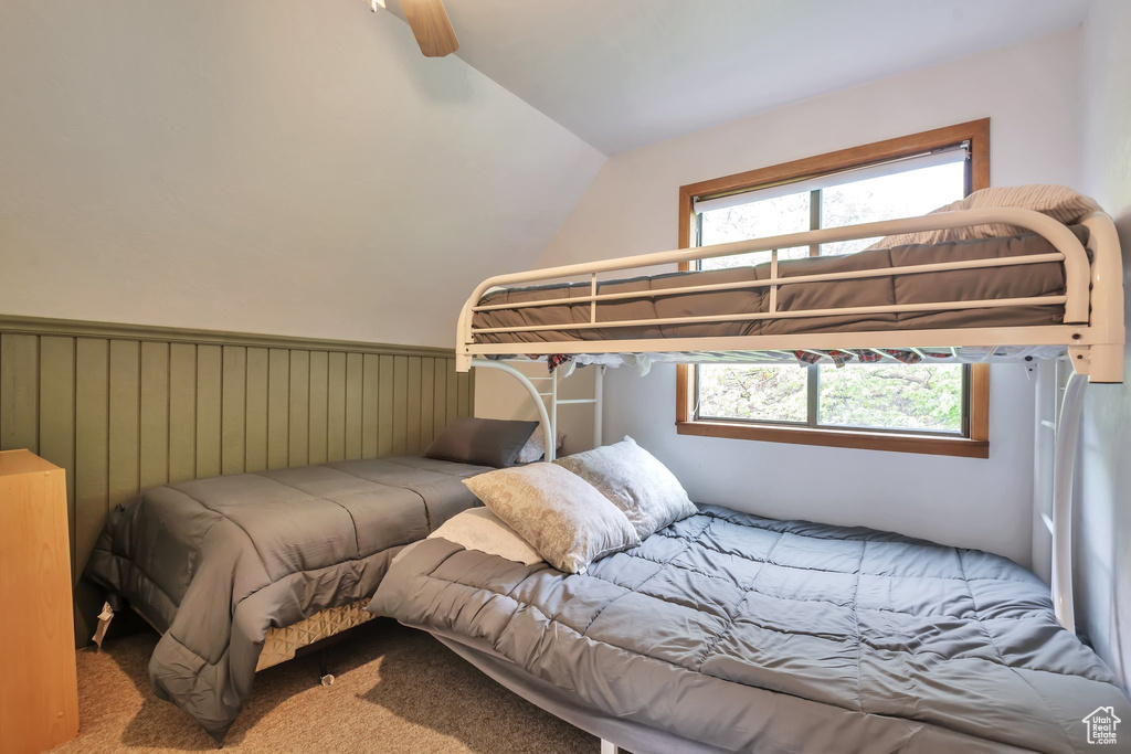 Carpeted bedroom featuring vaulted ceiling and a ceiling fan