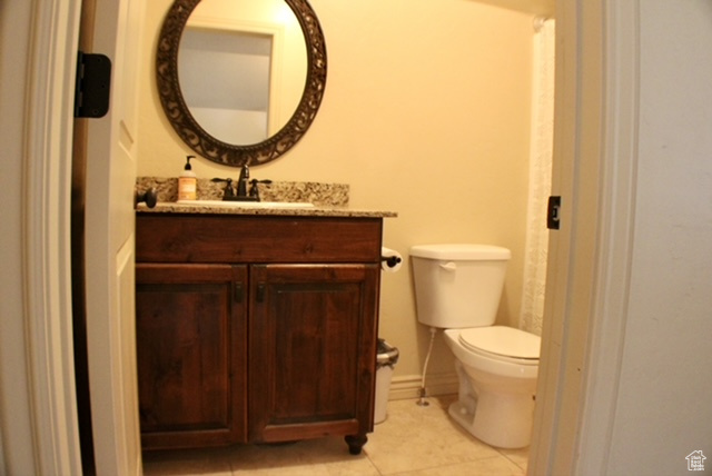 Half bathroom with tile patterned flooring, vanity, and toilet