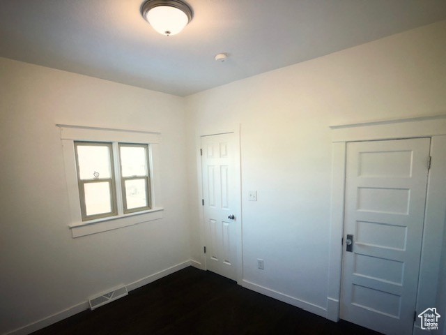 Unfurnished bedroom with dark wood-style flooring and baseboards