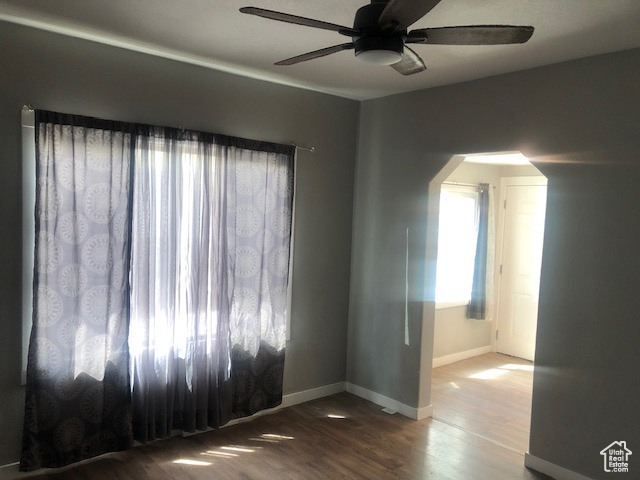 Empty room featuring a ceiling fan, baseboards, and wood finished floors