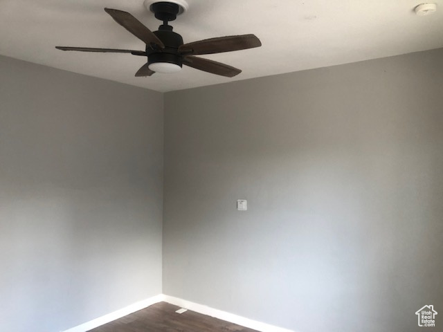 Unfurnished room with a ceiling fan, baseboards, dark wood-style floors, and a smoke detector