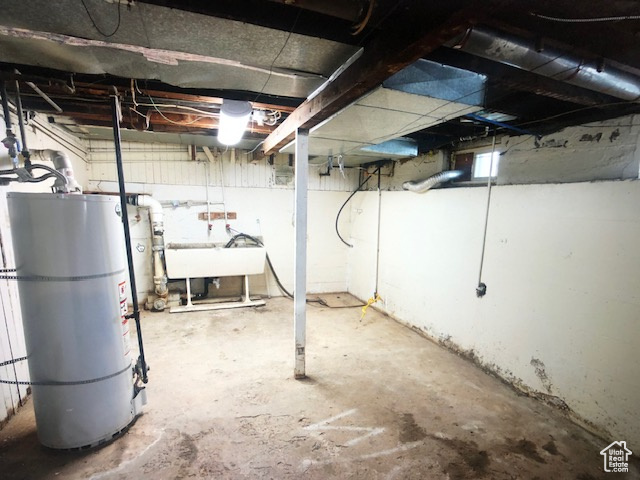 Unfinished below grade area with water heater and a sink