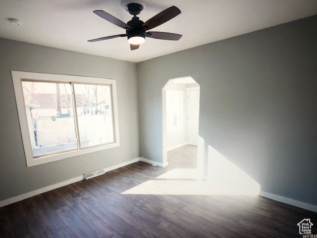 Unfurnished room with arched walkways, baseboards, wood finished floors, and a ceiling fan