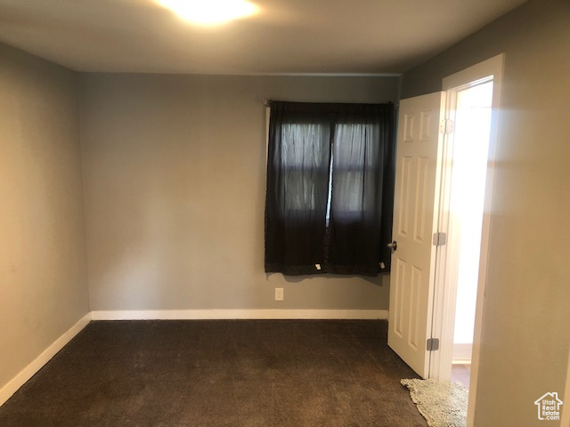 Spare room with dark colored carpet and baseboards