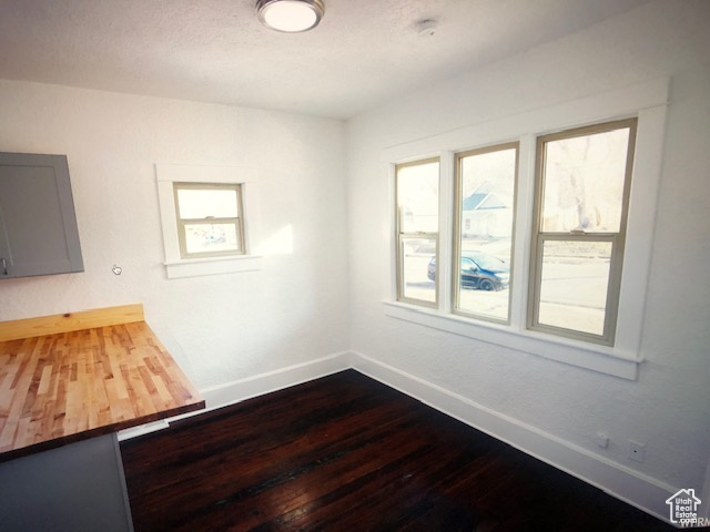 Unfurnished room featuring baseboards and dark wood finished floors