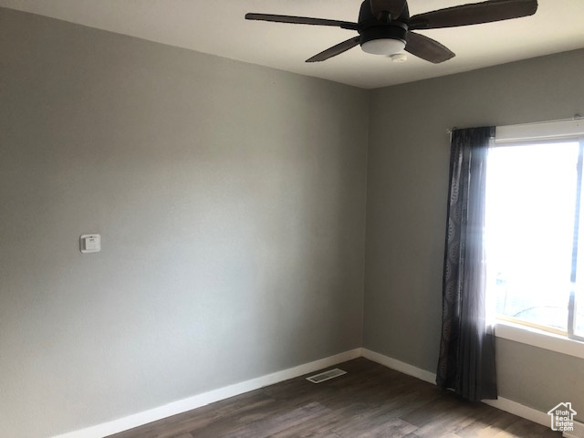 Unfurnished room with dark wood-style flooring, baseboards, and a ceiling fan