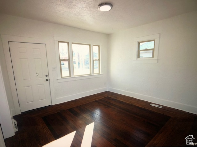 Foyer entrance featuring baseboards, wood finished floors, and a textured ceiling