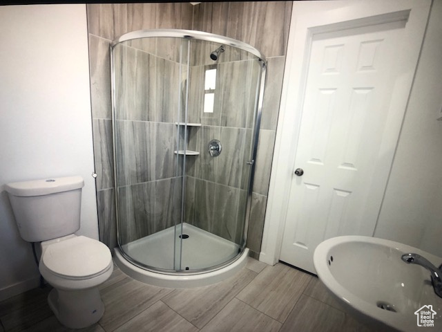 Full bath with a shower stall, a sink, toilet, and baseboards