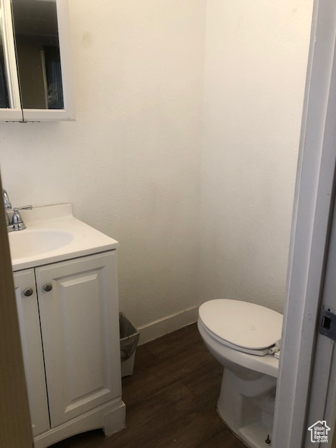 Bathroom featuring vanity, wood finished floors, toilet, and baseboards