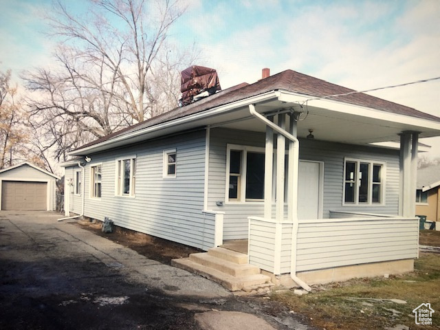 View of property exterior with asphalt driveway, an outdoor structure, a chimney, and a garage