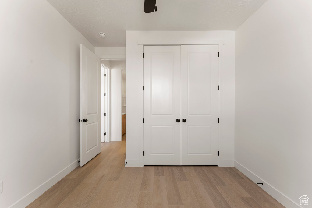Unfurnished bedroom featuring light wood-style flooring, baseboards, a closet, and a ceiling fan