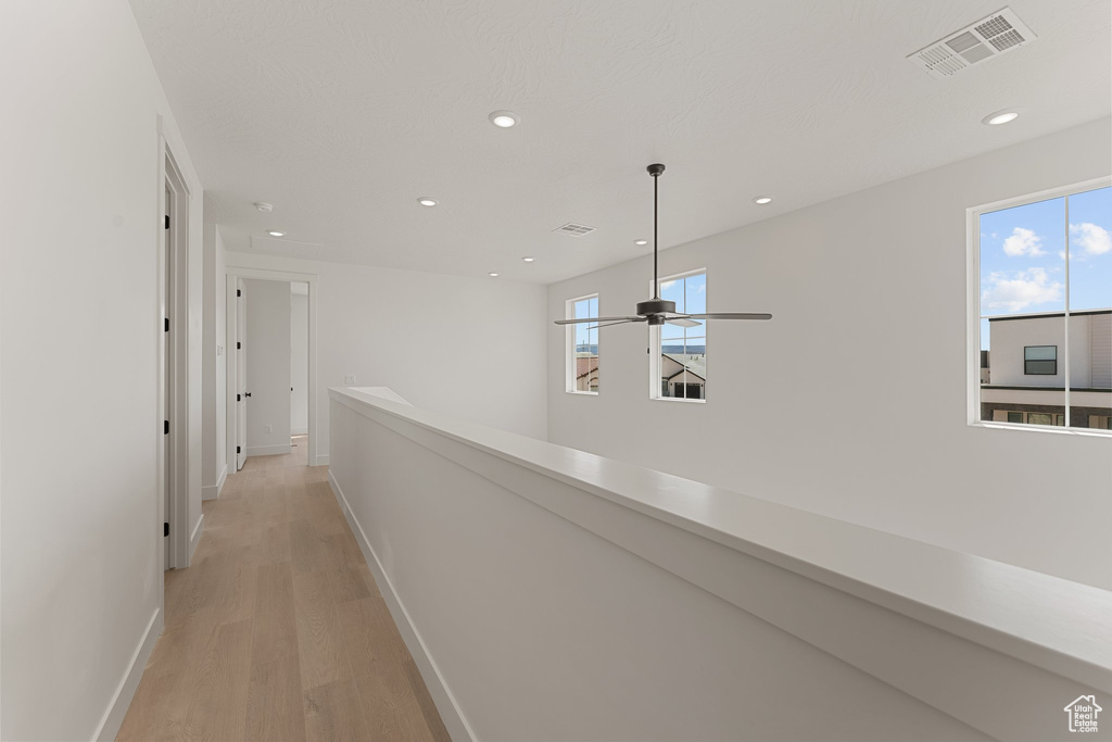 Corridor with light wood-style flooring, baseboards, recessed lighting, and an upstairs landing