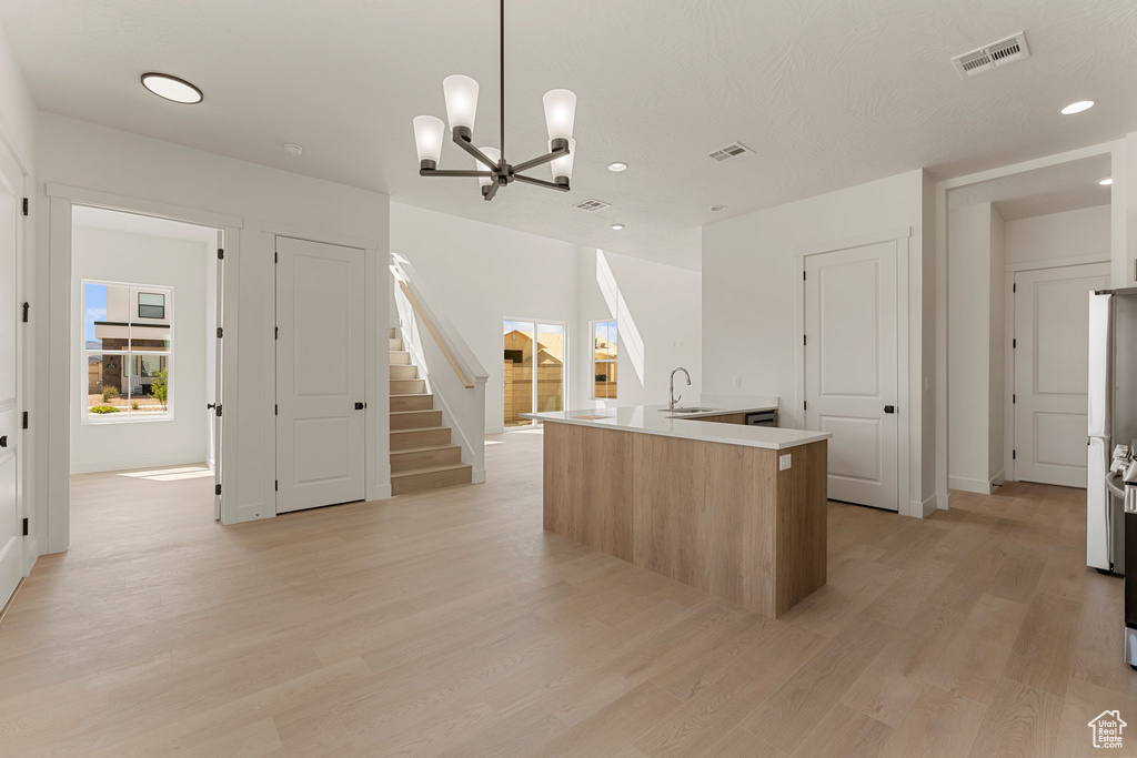 Kitchen featuring a center island with sink, recessed lighting, light wood-style flooring, a chandelier, and a sink