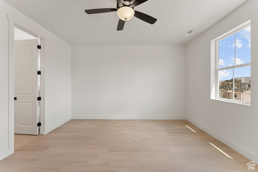 Spare room featuring light wood-style floors, ceiling fan, and baseboards