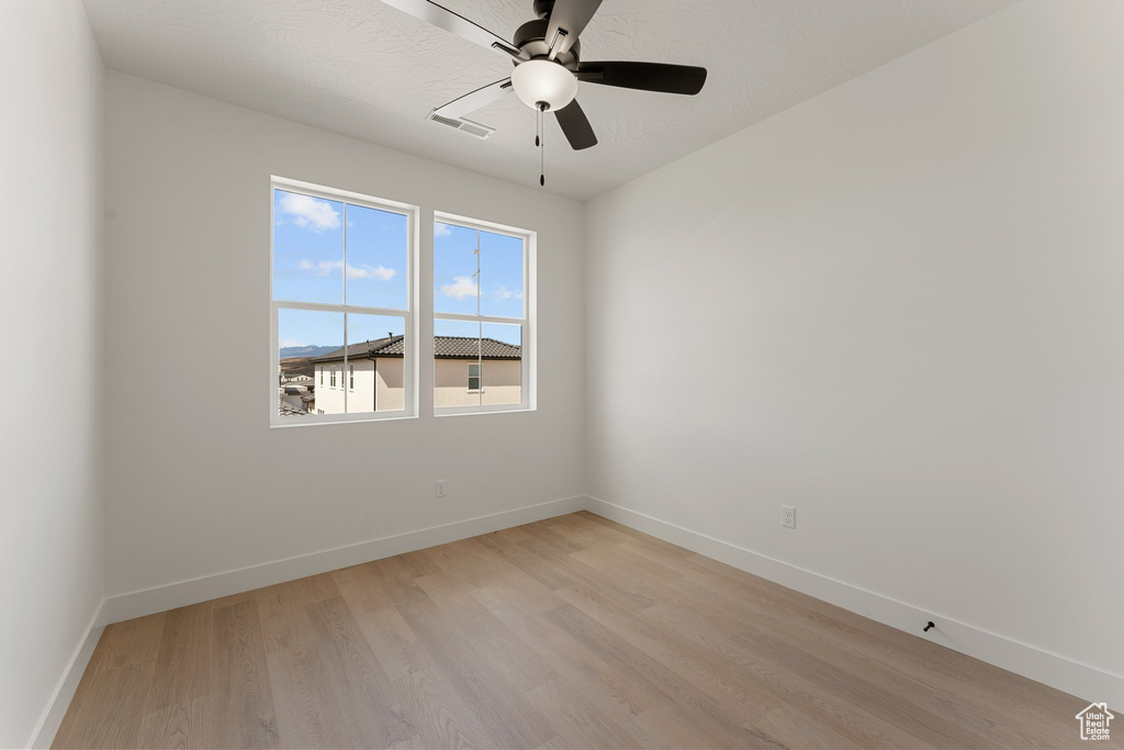 Spare room featuring baseboards, light wood-type flooring, and a ceiling fan