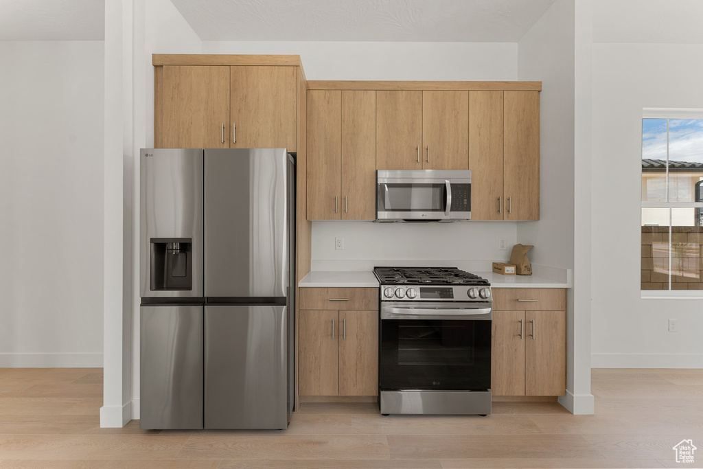 Kitchen featuring appliances with stainless steel finishes, light countertops, baseboards, and light wood-style floors