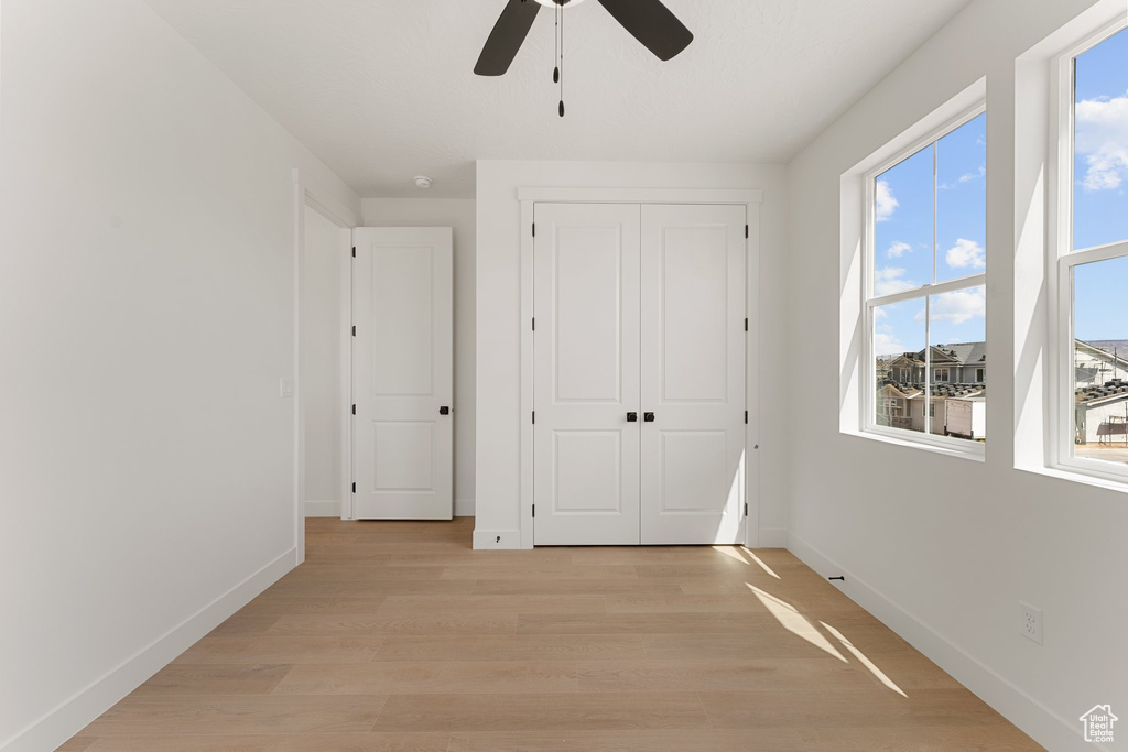 Unfurnished bedroom featuring light wood-type flooring, baseboards, a closet, and a ceiling fan