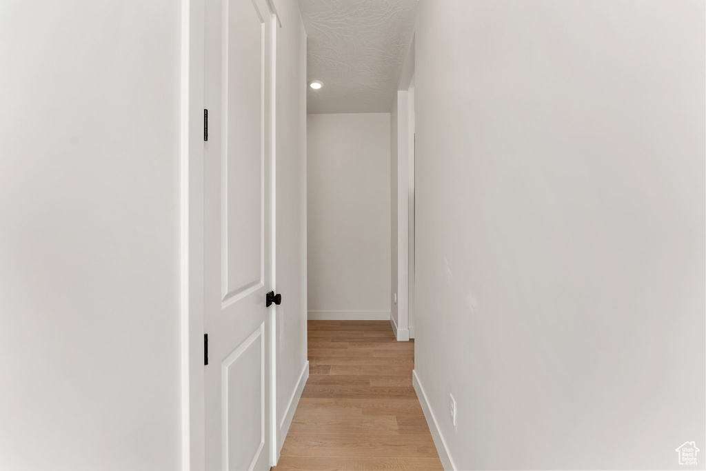 Hallway with light wood-style floors, baseboards, and recessed lighting