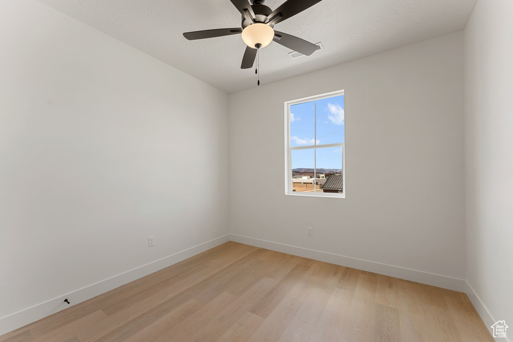 Spare room with baseboards, light wood-style floors, and ceiling fan