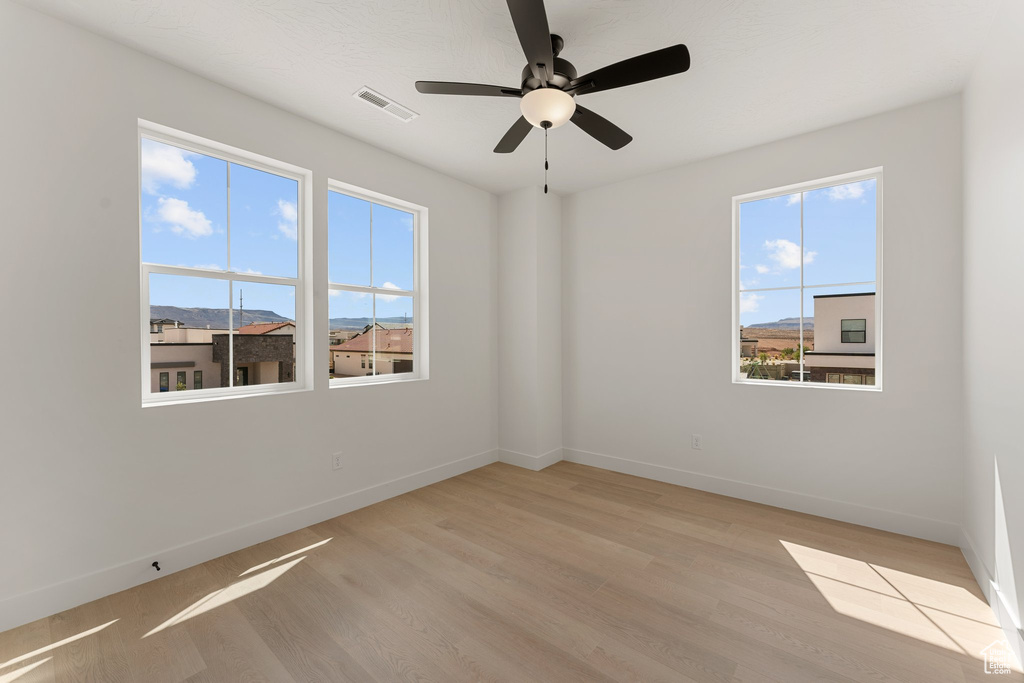 Unfurnished room featuring baseboards, light wood finished floors, and ceiling fan