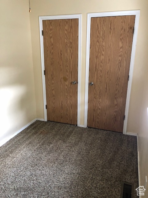 Unfurnished bedroom featuring multiple closets, carpet flooring, and baseboards