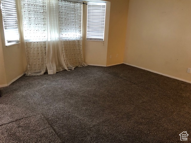 Spare room with dark colored carpet, healthy amount of natural light, and baseboards