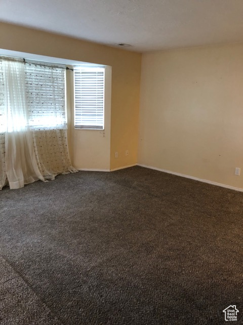 Empty room with dark colored carpet and baseboards