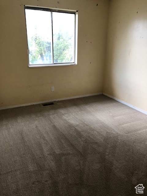 Carpeted spare room featuring baseboards