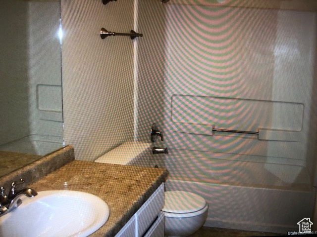 Bathroom with toilet, vanity, tub / shower combination, and tile walls