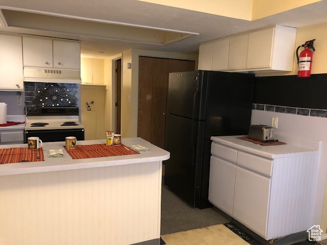 Kitchen featuring electric range oven, under cabinet range hood, light countertops, and freestanding refrigerator
