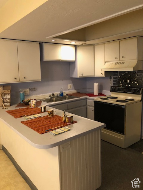 Kitchen featuring electric stove, white cabinets, a sink, and under cabinet range hood