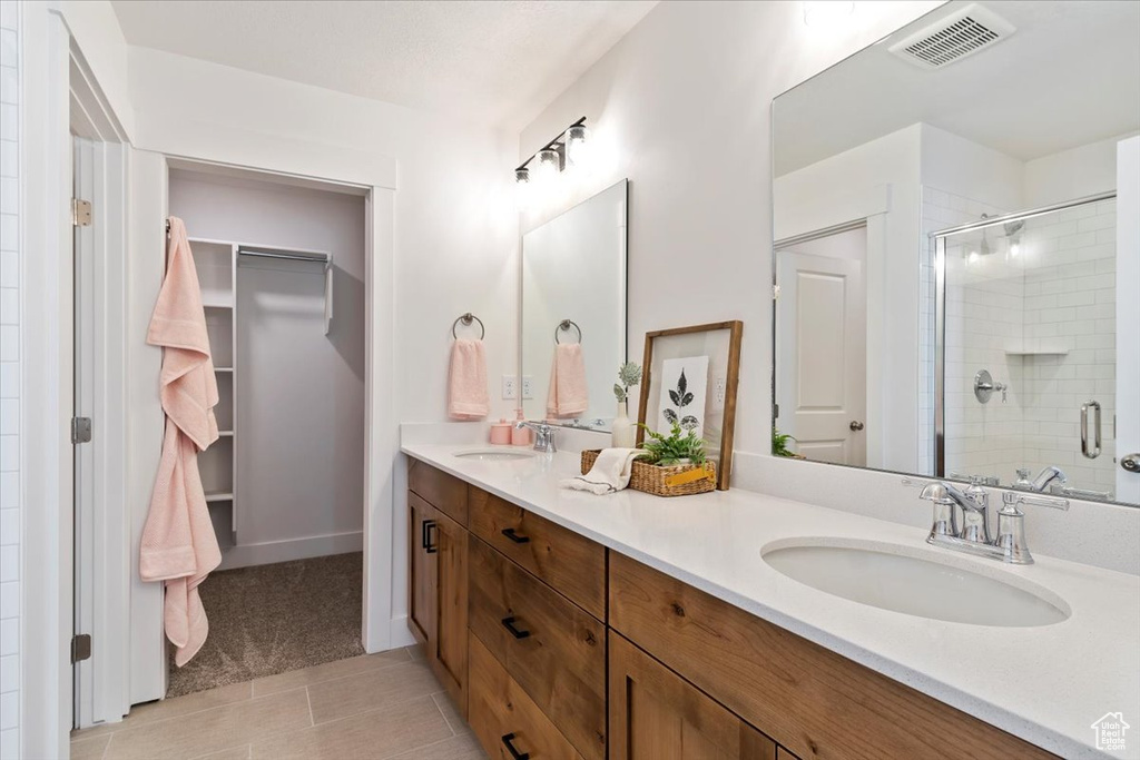 Full bath featuring a stall shower, double vanity, and tile patterned flooring