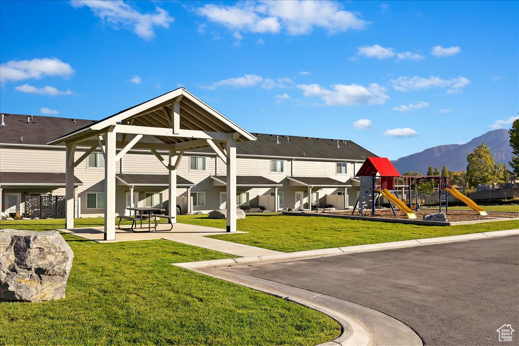 Back of house with a mountain view, a playground, and a yard