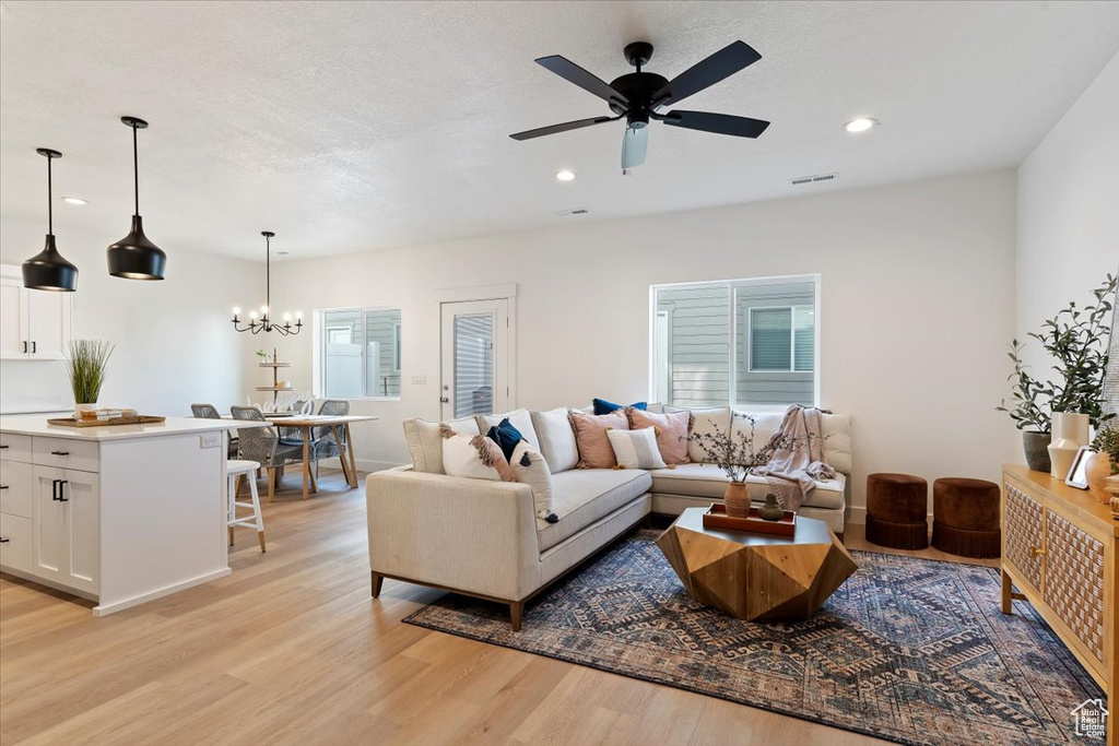 Living area featuring light wood-style floors, recessed lighting, a ceiling fan, and a chandelier