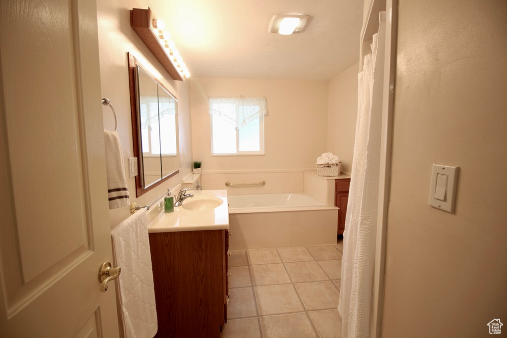 Bathroom featuring tile patterned flooring, vanity, and a bath