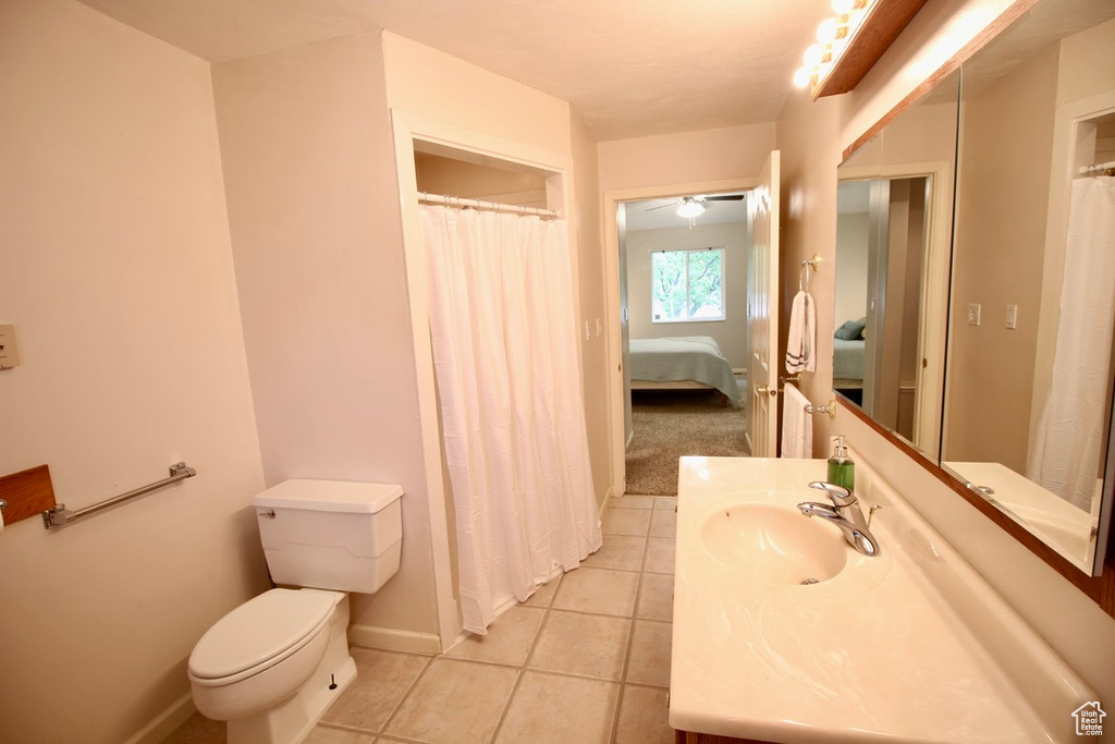 Bathroom with tile patterned floors, vanity, toilet, baseboards, and a shower with shower curtain
