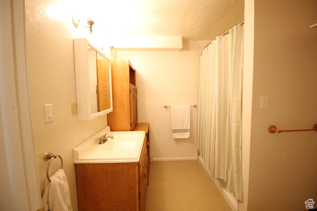 Full bath featuring vanity, a shower with curtain, and baseboards